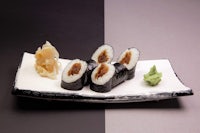 japanese sushi on a white plate with a black background